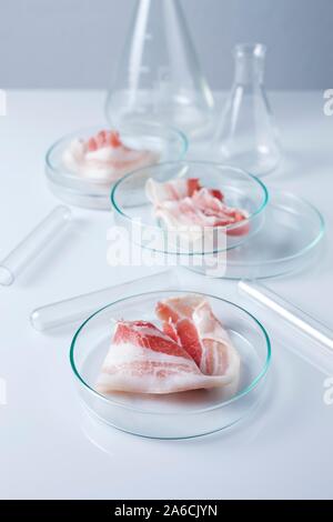 Immagine concettuale del finto di carne con articoli di vetreria di laboratorio. Foto Stock