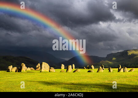 Rainbow su Castlerigg Stone Circle il solstizio d'estate vigilia con sole e nuvole scure in Monti Pennini Lake District Inghilterra Keswick Foto Stock