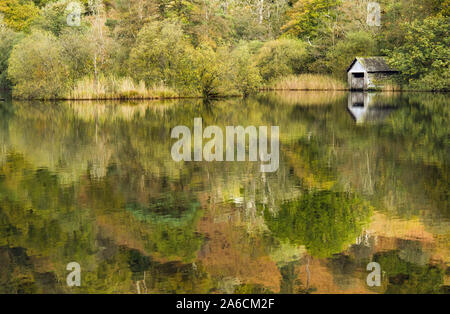 La Rydal acqua Boathouse insieme con gli alberi e le loro riflessioni nel lago ancora, Parco Nazionale del Distretto dei Laghi in Cumbria a inizio autunno Foto Stock