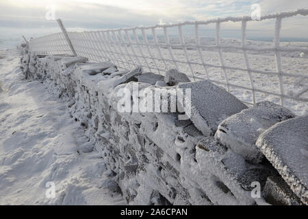 In pietra a secco e la parete di recinto di filo ricoperto di trasformata per forte gradiente di brina sui Whernside tappezzate in neve e ghiaccio metà inverno Yorkshire Dales Foto Stock