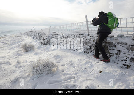 Walker prendendo fotografie di trasformata per forte gradiente frost a secco su un muro di pietra, Whernside tappezzate in neve e ghiaccio metà inverno Yorkshire Dales Foto Stock