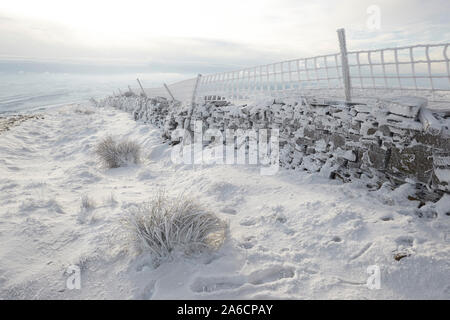 In pietra a secco e la parete di recinto di filo ricoperto di trasformata per forte gradiente di brina sui Whernside tappezzate in neve e ghiaccio metà inverno Yorkshire Dales Foto Stock