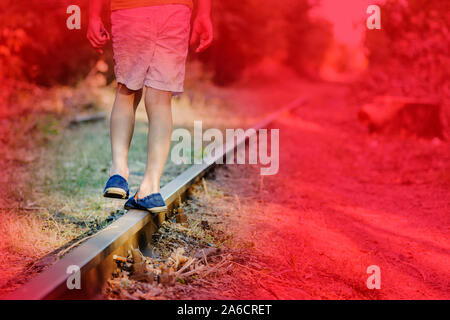 Il bambino a camminare sulla linea ferroviaria. Un piccolo ragazzo a piedi sulla ferrovia una zona di maggior rischio. Foto Stock