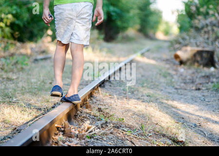 Il bambino a camminare sulla linea ferroviaria. Un piccolo ragazzo a piedi sulla ferrovia una zona di maggior rischio. Foto Stock