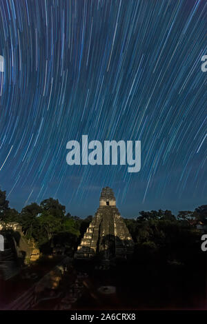 Tempio che io, Tempio della Jaguar, dalla luce della luna piena di notte con tracce stellari, Parco Nazionale di Tikal, Guatemala. Foto Stock