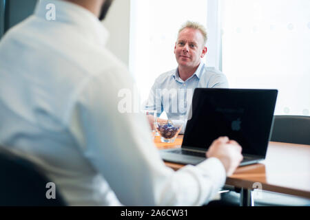 Due persone si sedette ad un tavolo avente una riunione o un colloquio di lavoro Foto Stock