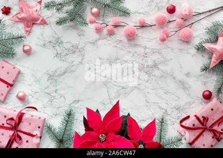 Natale lay piatto con telaio realizzato dalla vibrante color fucsia, poinsettia avvolto confezioni regalo, verde naturale Abete rami e ciondoli di rosa. Copy-spazio Foto Stock