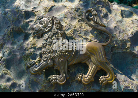 Close-Up di metallo Lion Statua collocata su un muro di pietra Foto Stock