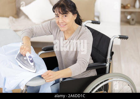 Disabilitato donna matura durante la stiratura a casa Foto Stock