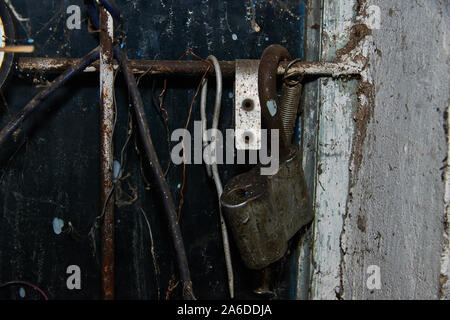 Vecchio lucchetto arrugginito sulla parete closeup nella vecchia officina in Russia Foto Stock