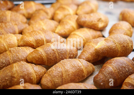 Molti di croissant. Pasticceria calda giacciono sulla vetrina nella caffetteria. Panini e bagel in negozio. Foto Stock