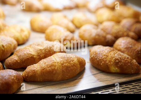 Molti di croissant. Pasticceria calda giacciono sulla vetrina nella caffetteria. Panini e bagel in negozio. Foto Stock