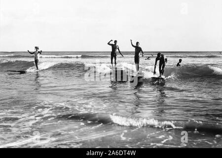 Vintage foto di surf da spiaggia di Waikiki a Honolulu, Hawaii di surfisti sulla tavola da surf in legno la condivisione di un onda. Foto Stock