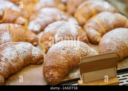 Molti di croissant. Pasticceria calda giacciono sulla vetrina nella caffetteria. Panini e bagel in negozio. Foto Stock