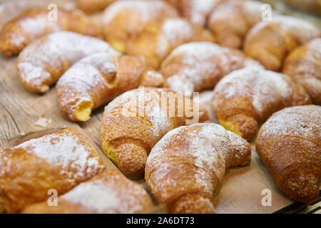 Molti di croissant. Pasticceria calda giacciono sulla vetrina nella caffetteria. Panini e bagel in negozio. Foto Stock