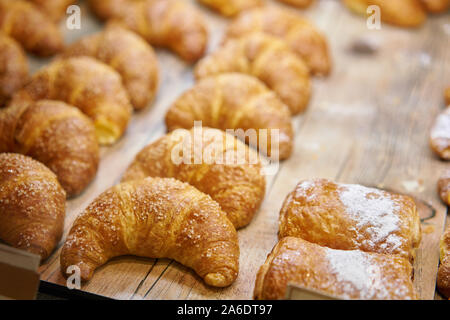 Molti di croissant. Pasticceria calda giacciono sulla vetrina nella caffetteria. Panini e bagel in negozio. Foto Stock