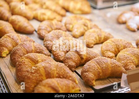 Molti di croissant. Pasticceria calda giacciono sulla vetrina nella caffetteria. Panini e bagel in negozio. Foto Stock