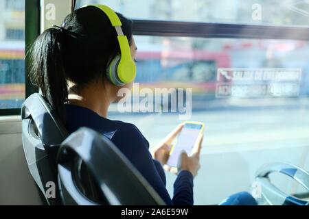 Donna con cuffie per ascoltare musica durante gli spostamenti verso in autobus Foto Stock