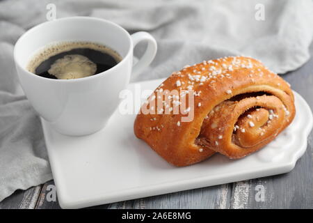 Torta svedese alla cannella e una tazza di caffè nero Foto Stock