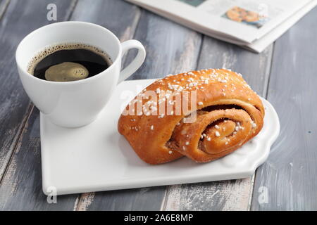 Torta svedese alla cannella e una tazza di caffè nero Foto Stock