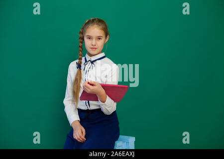 Schoolgirl ragazza sta con un internet tablet presso il consiglio di classe Foto Stock