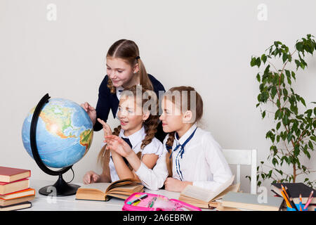 Le tre ragazze a guardare il mondo in classe di geografia Foto Stock