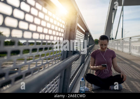 Esercizio al tramonto con belle, sport donna. Donna fitness jogging, l'allenamento il concetto di benessere. Femminile ascoltare musica durante il jogging Foto Stock