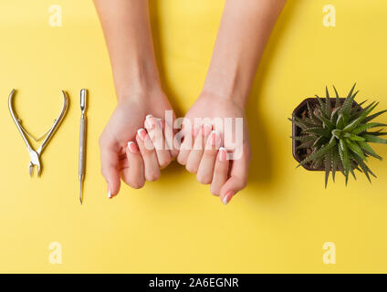 Neat bella manicure francese sulle mani di una giovane donna. Utensile per il taglio di unghie. Il minimalismo concetto per la cura delle unghie. Foto Stock