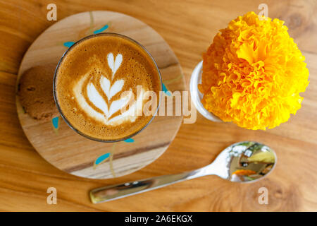 Tazza di caffè piccolo in un supporto di legno su un tavolo di legno in una caffetteria. Tagete in un bicchiere. Vista dall'alto. Con lo spazio. Foto Stock