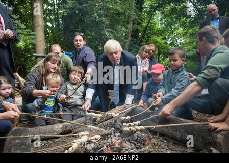 Shooters Hill bosco ad ampi orizzonti centro dell'ambiente, a sud-est di Londra, Regno Unito. Il 30 luglio, 2015. Nella foto: Boris cuoce il suo pane su un falò Foto Stock