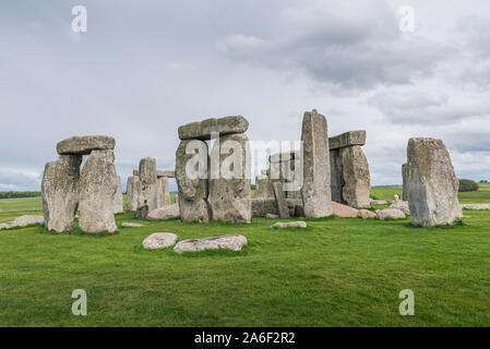 Stonehenge su un nuvoloso e ventoso giorno di primavera. Antiche rovine nel Wiltshire, Inghilterra, con nessun popolo o di turisti. Erba verde in primo piano Foto Stock