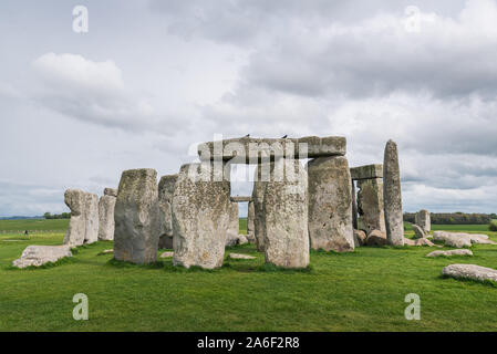 Stonehenge su un nuvoloso e ventoso giorno di primavera. Antiche rovine nel Wiltshire, Inghilterra, con nessun popolo o di turisti. Erba verde in primo piano Foto Stock