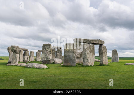 Stonehenge su un nuvoloso e ventoso giorno di primavera. Antiche rovine nel Wiltshire, Inghilterra, con nessun popolo o di turisti. Erba verde in primo piano Foto Stock