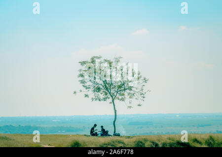 Due giovani uomo seduto sotto agli alberi, a Jaddih collina calcarea, Bangkalan, isola Madura, East Java, Indonesia Foto Stock