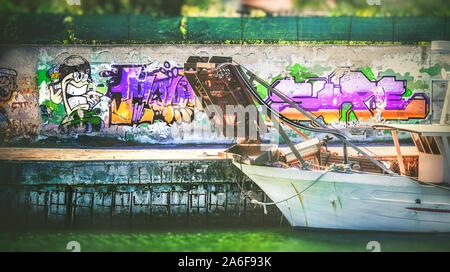 Vecchia città in barca dal molo del porto di graffiti colorati in verde Foto Stock