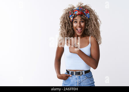 Sorpreso entusiasta afro-americano ricci bionda ragazza con piercing, handband, affannosa stupito, rivolta a sinistra si chiedeva e impressionato, condivisione Foto Stock