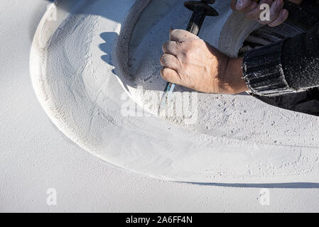 Primo piano di un artista curve carving in una pietra bianca con gesti precisi utilizzando uno scalpello. Foto Stock