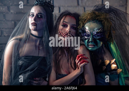 Tre donne in costumi di carnevale di un vampiro sposa, sanguinosa e mutante strega. Concetto di Halloween. Foto Stock