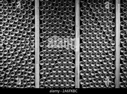 Pile di bottiglie di vino piatto in scaffalature in legno nella vecchia cantina o grotta Foto Stock