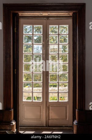 Scolpita in legno e porte vetrate che portano dalla vecchia casa in giardino con la luce solare Foto Stock