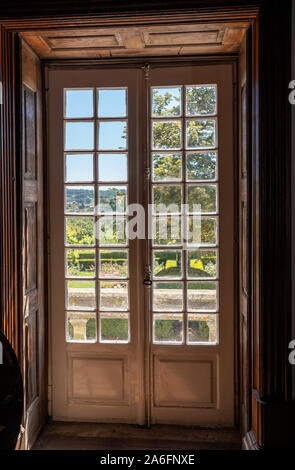 Scolpita in legno e porte vetrate che portano dalla vecchia casa in giardino con la luce solare Foto Stock