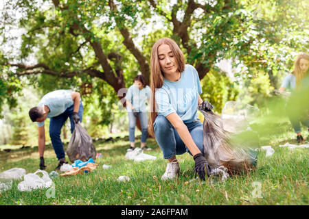 Il volontariato. I giovani volontari all'aperto ragazza di close-up di prelievo gioiosa di lettiera Foto Stock