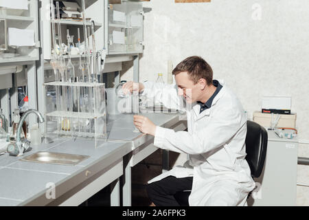 Giovane scienziato conduce esperimenti di chimica con liquidi nel laboratorio di scienze Foto Stock