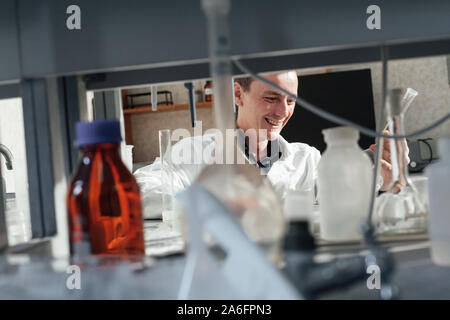 Giovane scienziato conduce esperimenti di chimica con liquidi nel laboratorio di scienze Foto Stock