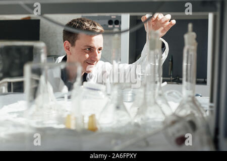 Giovane scienziato conduce esperimenti di chimica con liquidi nel laboratorio di scienze Foto Stock