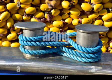 La cima di ormeggio avvolto intorno in acciaio inox bollard sul trincarino di barca da pesca con net e galleggia dietro Foto Stock