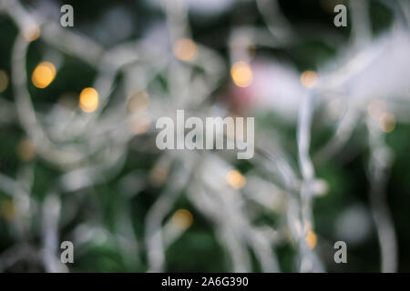 Defocalizzata bokeh foto di abbondanza di luci di Natale su un verde albero di Natale. Le luci sono di colore bianco e di colore giallo. Bella vacanza sfocata foto. Foto Stock