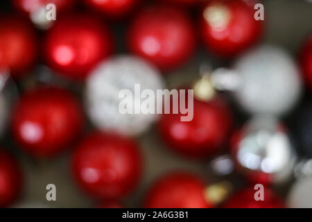 Defocalizzata bokeh foto di abbondanza di colorate decorazioni di Natale in rosso, argento, grigio e bianco colori. Bella shiny ancora sfocata vacanza astratto a tema Foto Stock