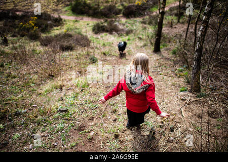 Graziosa bambina saltando in molto fangoso pozza giocando con il suo cane nel freddo autunno Meteo in Stoke on Trent, Staffordshire, Hulme Quarry Foto Stock