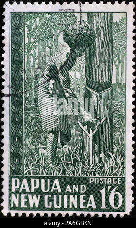 La raccolta del lattice di gomma da albero su vintage timbro di Papua Foto Stock